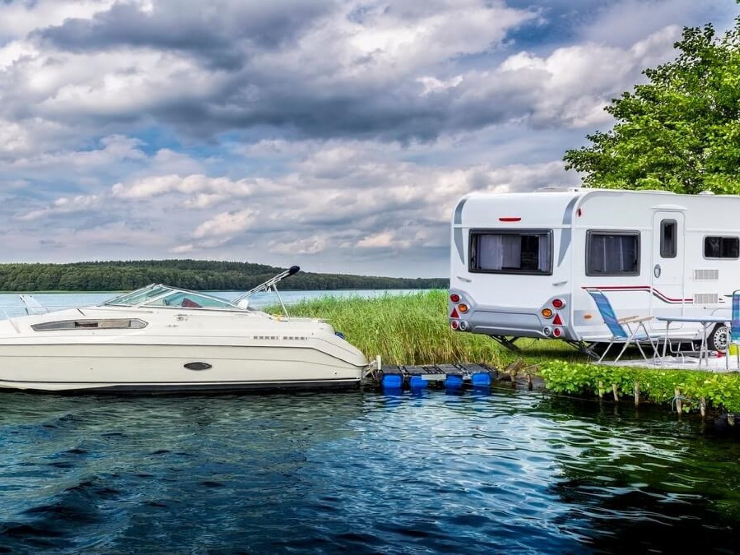 Picture of a boat in water next to a RV on land.
