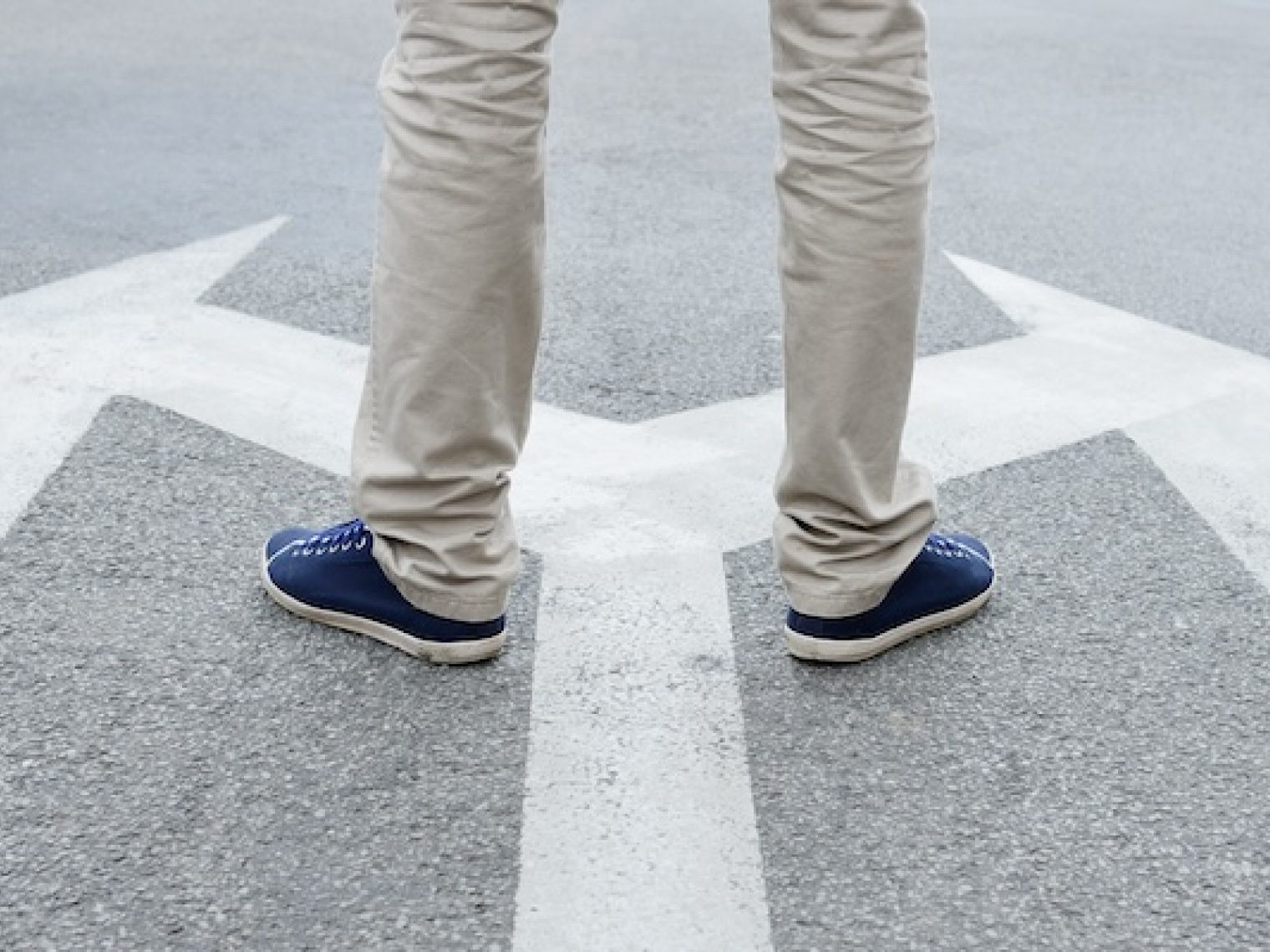 Man standing on arrows painted on asphalt.